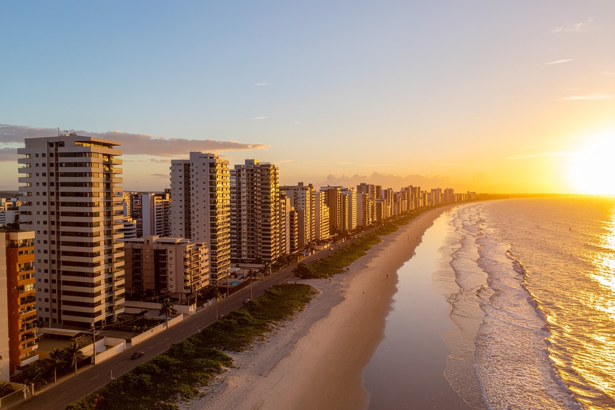 Vista aérea da orla de Itapema ao entardecer, prédios residenciais e praia